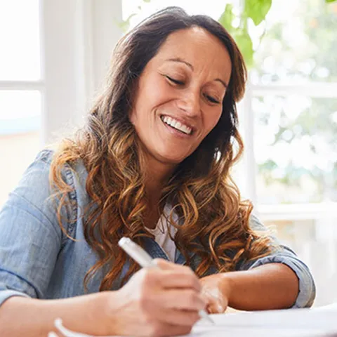 Woman writing and smiling.