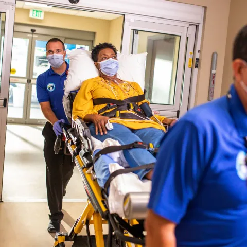 Women being taken in on a stretcher through emergency department